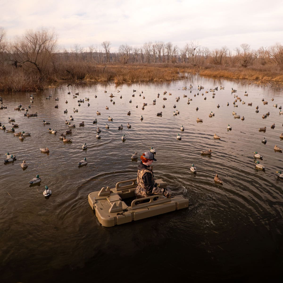 Drone view of a large duck decoy spread on open water around a boat blind